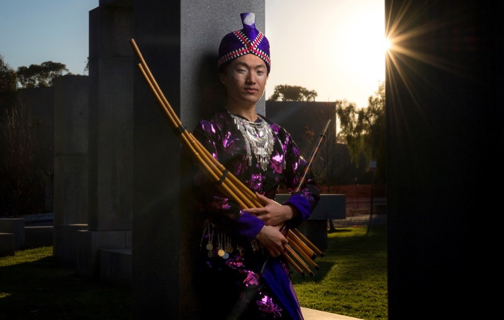 UC San Diego senior Eugene Tsim Nuj Vang poses in traditional Hmong clothing to honor their heritage. They also hold a cherished instrument of their grandfather's called a qeej, a type of mouth organ made from bamboo pipes that has a 3,000-year history.